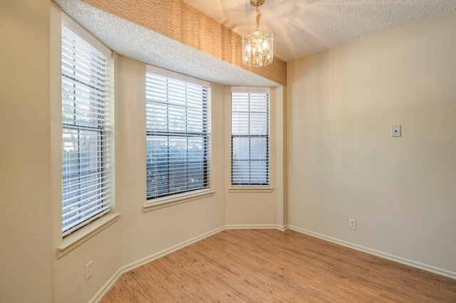 spare room featuring a chandelier, a textured ceiling, and hardwood / wood-style flooring