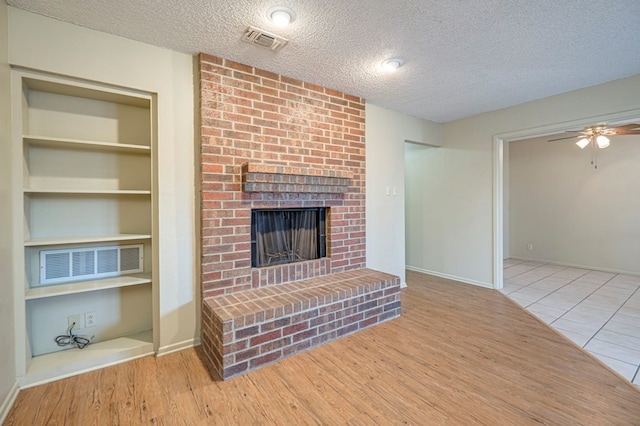 unfurnished living room with a textured ceiling, light hardwood / wood-style floors, and a brick fireplace