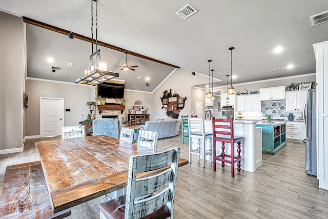 6811 W County Rd 41, Midland, TX 79707 - dining space with a ceiling fan, ornamental molding, a stone fireplace, light wood-style floors, and lofted ceiling