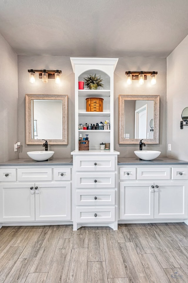 6811 W County Rd 41, Midland, TX 79707 - full bath featuring two vanities, wood finished floors, and a textured ceiling