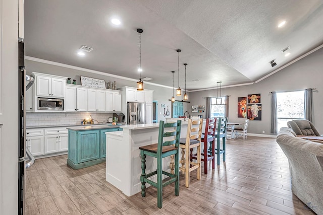 6811 W County Rd 41, Midland, TX 79707 - kitchen with a center island with sink, appliances with stainless steel finishes, open floor plan, crown molding, and light wood finished floors