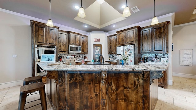 kitchen with a large island, visible vents, appliances with stainless steel finishes, a sink, and dark brown cabinets