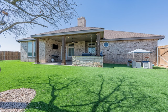 rear view of property featuring brick siding, a chimney, a ceiling fan, a patio area, and a fenced backyard