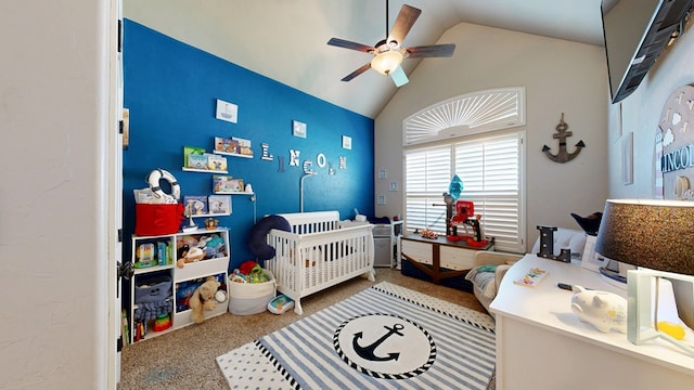 bedroom with lofted ceiling, ceiling fan, a crib, and carpet flooring