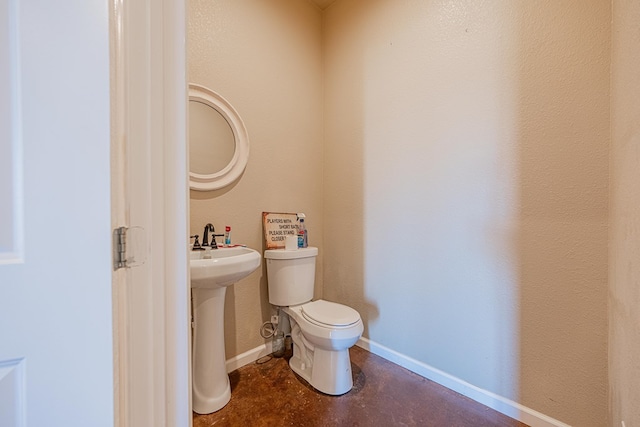 bathroom featuring concrete floors, a sink, toilet, and baseboards