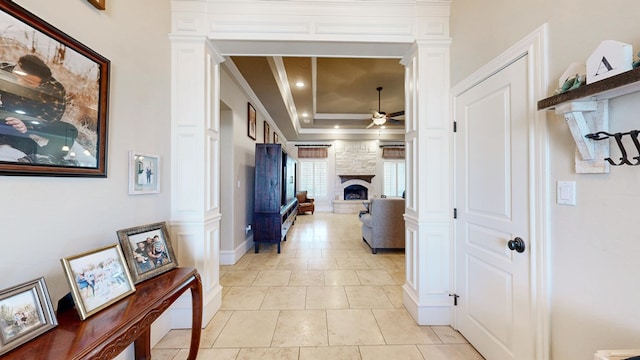 hall featuring crown molding, a tray ceiling, decorative columns, and recessed lighting