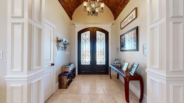 entryway featuring arched walkways, french doors, lofted ceiling, a chandelier, and baseboards