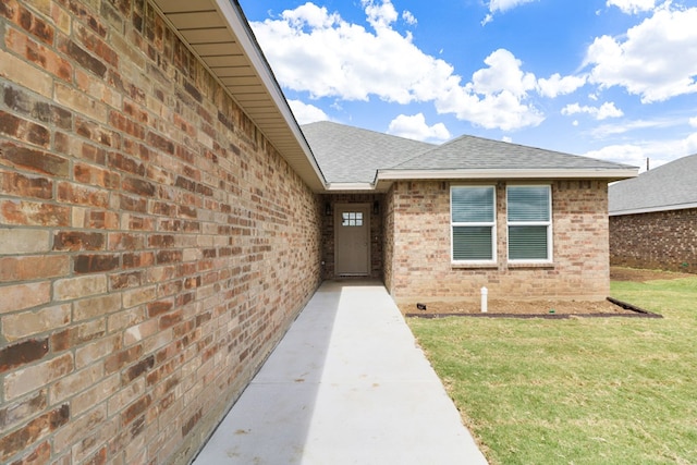 804 Bella Bvd, Coleman, TX 76834 - view of exterior entry featuring a shingled roof, brick siding, and a lawn