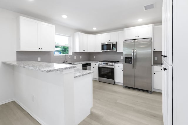 804 Bella Bvd, Coleman, TX 76834 - kitchen featuring appliances with stainless steel finishes, a peninsula, light wood-style flooring, tasteful backsplash, and recessed lighting