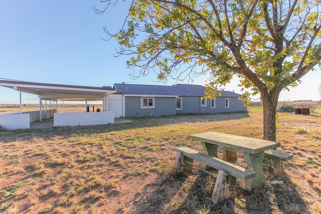 rear view of property with metal roof and a yard