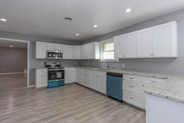 kitchen with stainless steel appliances, a sink, visible vents, white cabinetry, and light wood finished floors