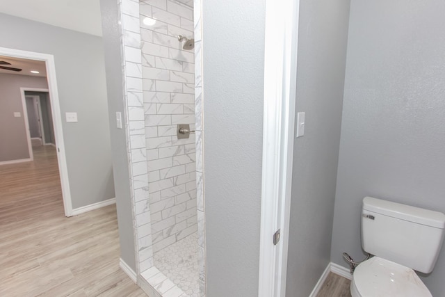 full bath featuring toilet, a shower stall, baseboards, and wood finished floors