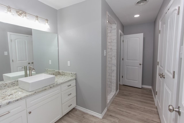 full bathroom featuring wood finished floors, vanity, visible vents, and baseboards