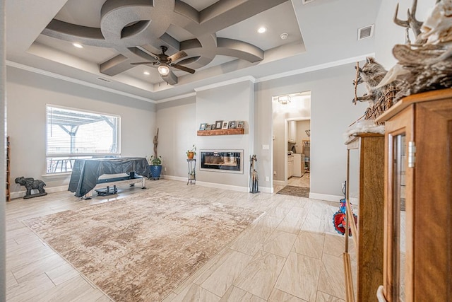 interior space with coffered ceiling, a towering ceiling, visible vents, ornamental molding, and a glass covered fireplace