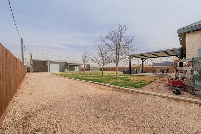 view of yard with a garage, a patio, a fenced backyard, and driveway