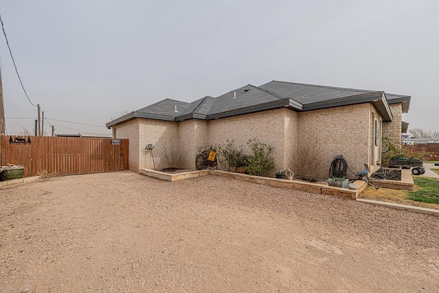 exterior space featuring brick siding, fence, and driveway