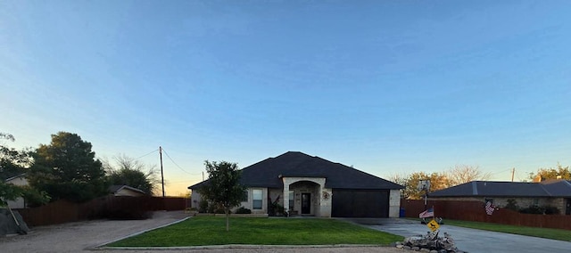 view of front of house with driveway, a garage, fence, and a yard