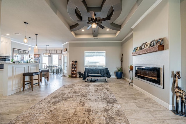 living room with ornamental molding, plenty of natural light, a glass covered fireplace, and baseboards