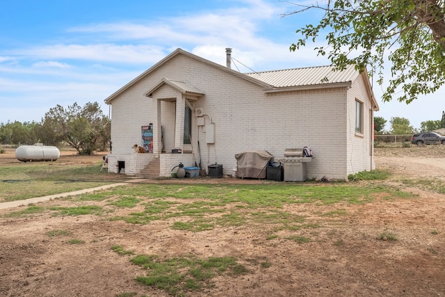 back of property with brick siding and metal roof