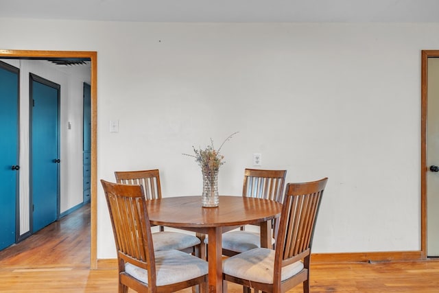 dining area with light wood-type flooring and baseboards