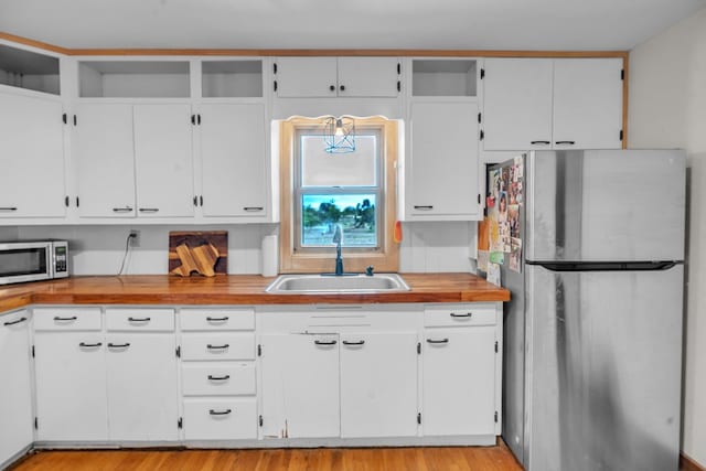 kitchen featuring stainless steel appliances, a sink, white cabinetry, and light wood-style flooring