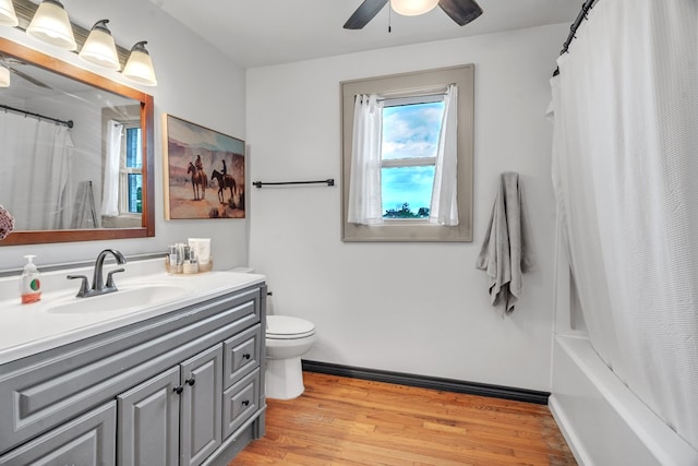bathroom with a ceiling fan, wood finished floors, toilet, vanity, and baseboards