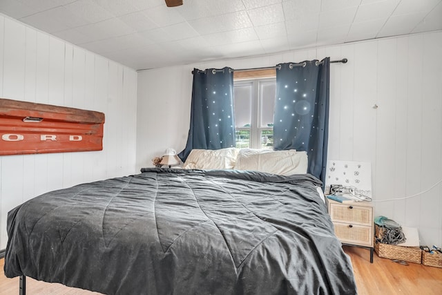 bedroom featuring wood finished floors and wooden walls