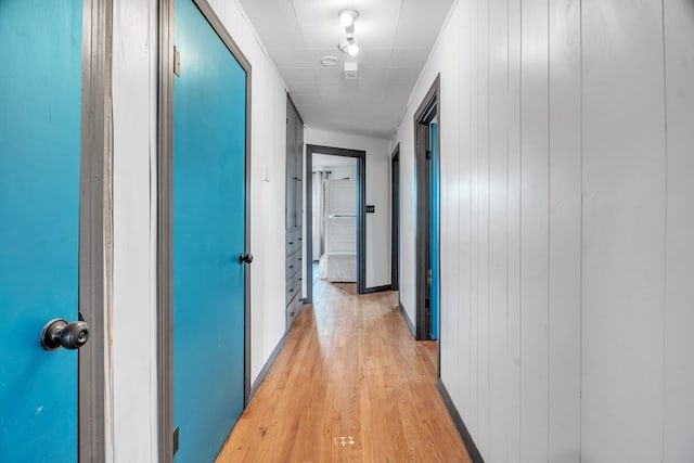 corridor featuring light wood-type flooring and baseboards