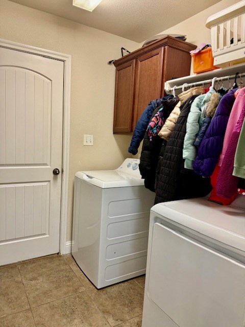 washroom with cabinet space, light tile patterned floors, and washing machine and clothes dryer