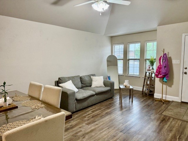 living room with baseboards, ceiling fan, wood finished floors, and high vaulted ceiling