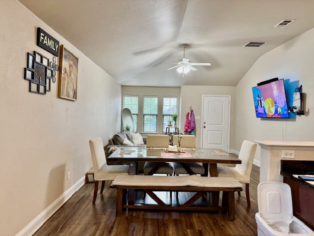 dining area with a ceiling fan, dark wood finished floors, lofted ceiling, and visible vents
