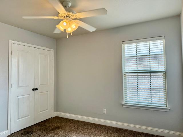606 Memorial Ct, Midland, TX 79706 - unfurnished bedroom with dark carpet, multiple windows, a closet, and baseboards
