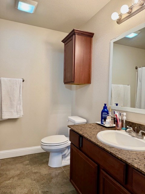 bathroom featuring vanity, baseboards, tile patterned floors, and toilet