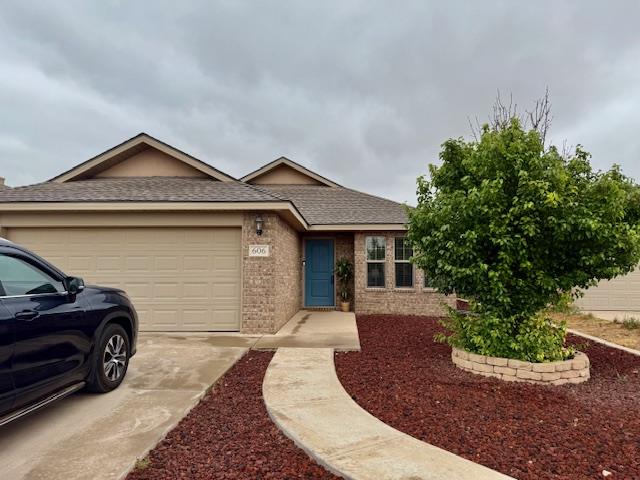 single story home featuring a shingled roof, an attached garage, concrete driveway, and brick siding