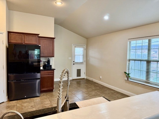 kitchen with baseboards, freestanding refrigerator, lofted ceiling, recessed lighting, and light tile patterned flooring