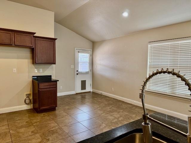 606 Memorial Ct, Midland, TX 79706 - kitchen with lofted ceiling, baseboards, dark countertops, and tile patterned flooring