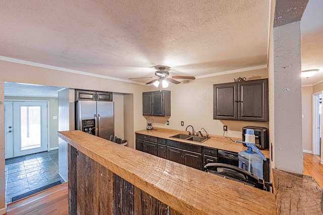 kitchen featuring stainless steel refrigerator with ice dispenser, light wood-type flooring, ornamental molding, a textured ceiling, and sink