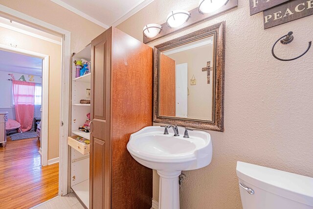 bathroom featuring toilet, ornamental molding, and hardwood / wood-style flooring