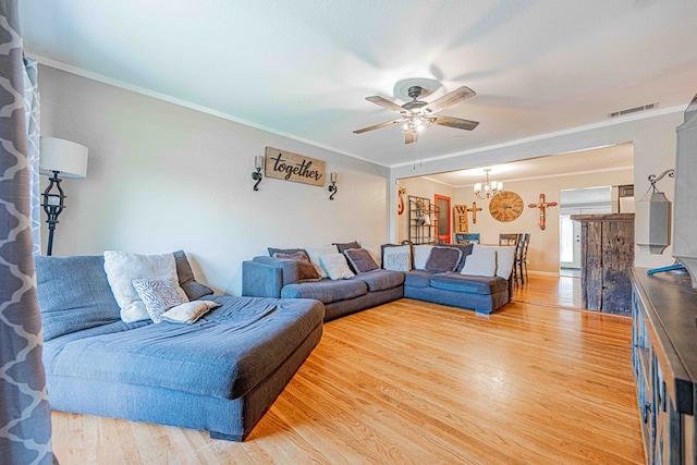 living room with hardwood / wood-style floors, ceiling fan with notable chandelier, and crown molding