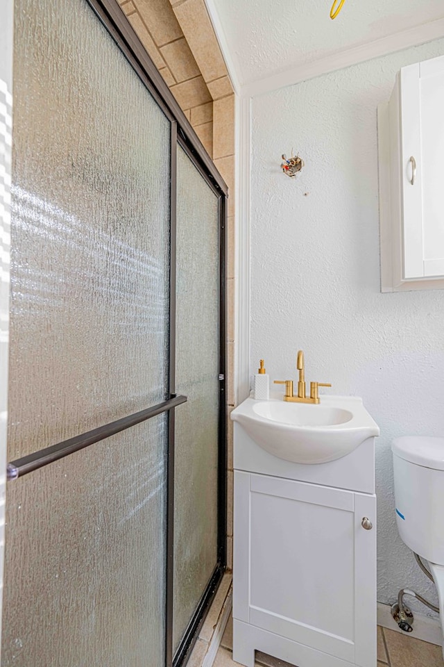 bathroom featuring tile patterned flooring, a textured ceiling, toilet, vanity, and a shower with shower door