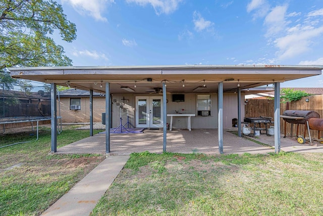 rear view of property with ceiling fan, a trampoline, a patio, and french doors