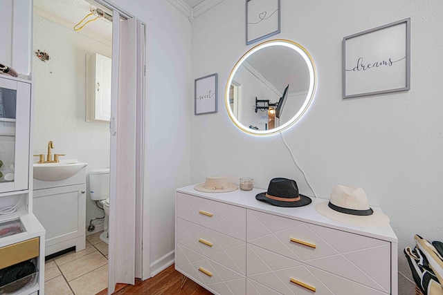 bathroom featuring wood-type flooring, vanity, ornamental molding, and toilet