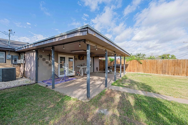 rear view of house with a lawn, french doors, cooling unit, and a patio