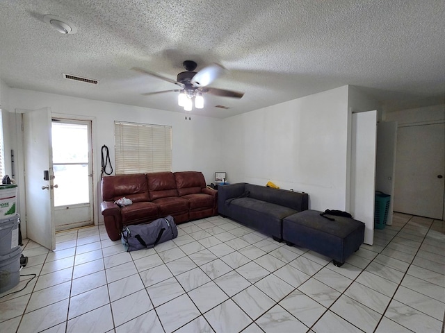 living area with a textured ceiling, a ceiling fan, and light tile patterned flooring