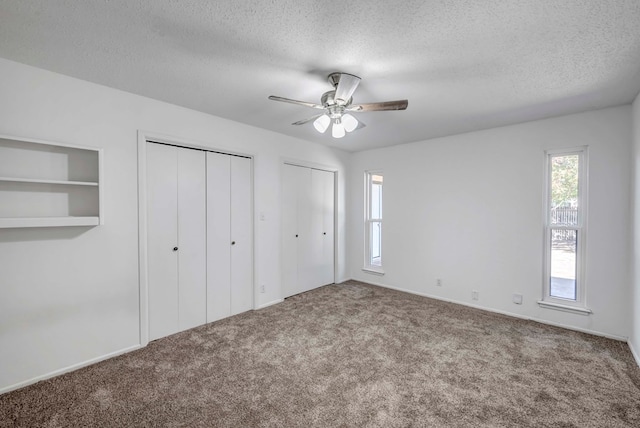 unfurnished bedroom featuring multiple closets, ceiling fan, carpet floors, and a textured ceiling