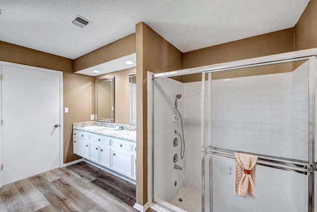 bathroom with vanity, an enclosed shower, hardwood / wood-style floors, and a textured ceiling