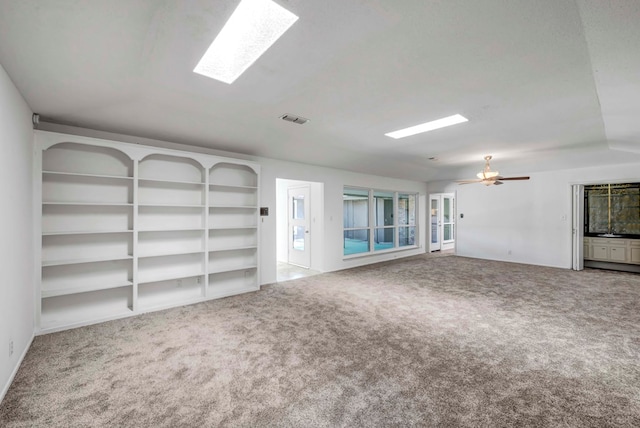 unfurnished room with carpet floors, ceiling fan, and a skylight