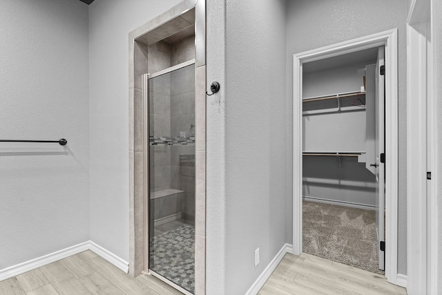 8514 Santa Isabella, Odessa, TX 79765 - full bath with a stall shower, a walk in closet, baseboards, wood finished floors, and a textured wall