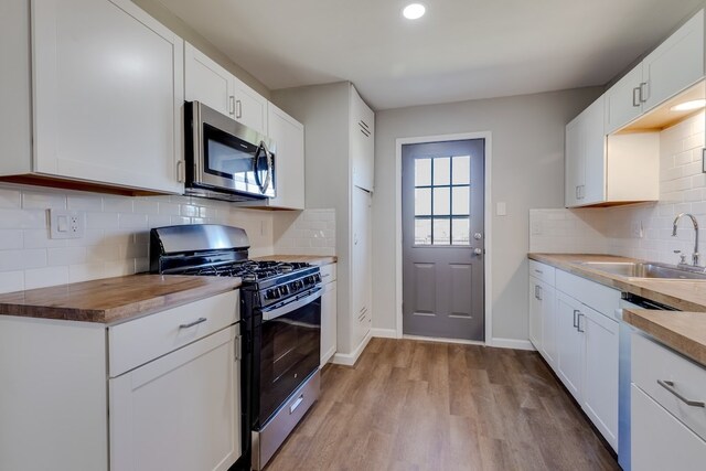 kitchen featuring tasteful backsplash, white cabinetry, light hardwood / wood-style flooring, and appliances with stainless steel finishes