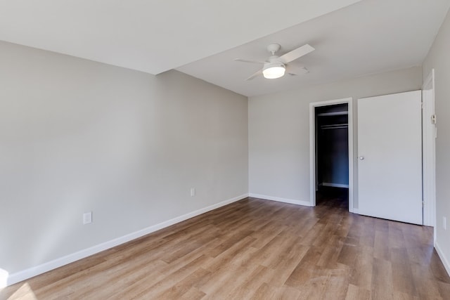 unfurnished bedroom featuring a walk in closet, ceiling fan, a closet, and light wood-type flooring